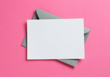 Pembe arka planda boş davetiye ve zarf, üst manzara. Tasarım için boşluk