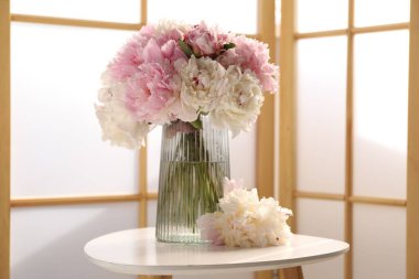 Beyaz masadaki vazodaki güzel şakayıklar.