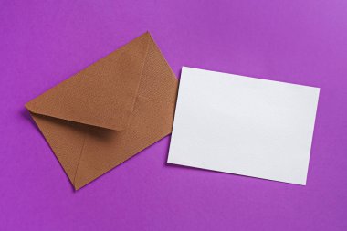 Mor arka planda boş davetiye ve zarf, düz yatış. Tasarım için boşluk