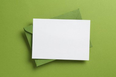 Yeşil arka planda boş davetiye ve zarf, üst manzara. Tasarım için boşluk