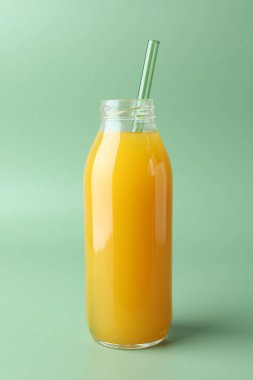 Yeşil arka planda cam şişede lezzetli mango suyu.