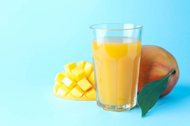 Bardakta lezzetli mango suyu ve açık mavi arka planda taze meyve, metin için yer