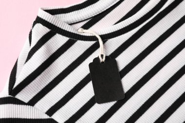 Pembe arka planda etiketli çizgili tişört, üst görünüm