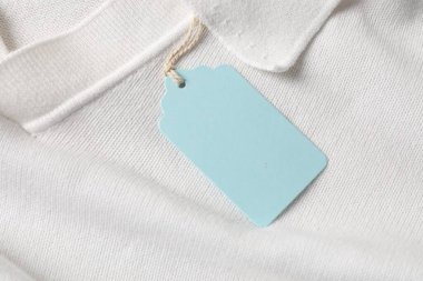 Beyaz giysinin üzerindeki karton etiket, üst görünümde