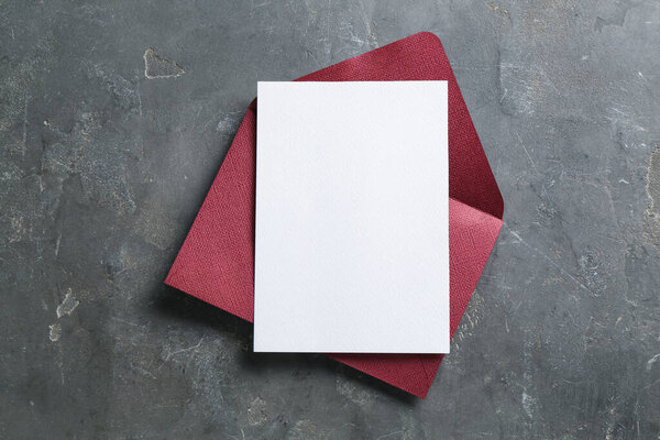 Blank invitation card and envelope on grey table, top view. Space for design