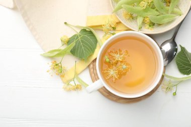 Taze ıhlamur çayı fincanda ve beyaz ahşap masada çiçekler düz yerde. Metin için boşluk