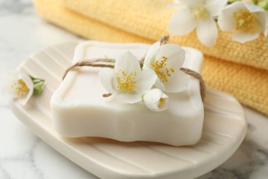 Sabun çubuğu ve yasemin çiçekleri beyaz mermer masada, yakın plan.