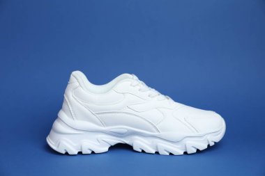 Mavi arka planda şık bir beyaz spor ayakkabı.