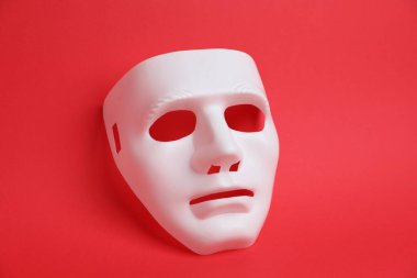 Kırmızı arka planda beyaz bir tiyatro maskesi, yukarıda.