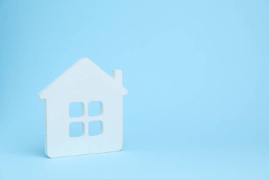 Açık mavi arka planda bir beyaz ev modeli, metin için boşluk