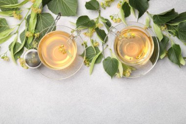 Taze ıhlamur çayı fincanda ve çiçekler açık gri masada, düz yerde. Metin için boşluk