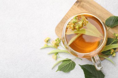 Taze ıhlamur çayı fincanda ve çiçekler açık gri masada, düz yerde. Metin için boşluk