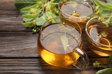 Fincanlarda taze ıhlamur çayı ve ahşap masada çiçekler, yakın plan. Metin için boşluk