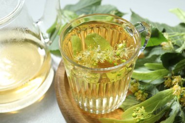 Lezzetli ıhlamur çayı, yapraklar ve çiçekler ışık masasında, yakın plan.