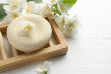 Sabun barı ve yasemin çiçekleri beyaz ahşap masada, yakın plan. Metin için boşluk