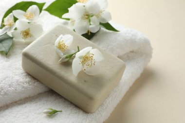 Bej arka planda sabun, havlu ve yasemin çiçekleri, yakın plan.