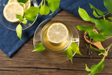 Limonlu yeşil çay ve ahşap masadaki yapraklar düzleşir.