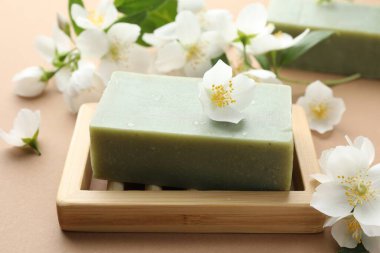 Açık kahverengi arka planda sabun ve yasemin çiçekleri, yakın plan.