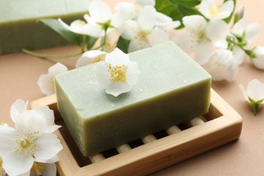 Açık kahverengi arka planda sabun ve yasemin çiçekleri, yakın plan.