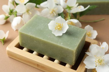 Açık kahverengi arka planda sabun ve yasemin çiçekleri, yakın plan.