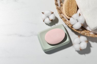 Sabun çubuğu, pamuk çiçekleri, beyaz mermer masada havlu ve fırça, düz yatak. Metin için boşluk