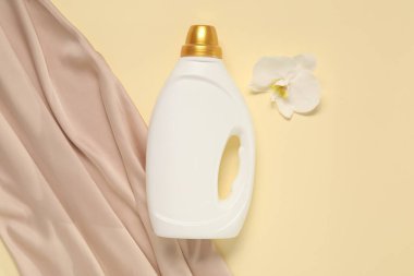 Bir şişe yumuşatıcı, orkide çiçeği ve bej arka planda renk bezi, düz yatıyordu.