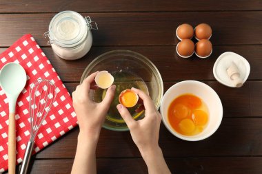 Tahta masada yumurta sarısını beyazdan ayıran kadın.
