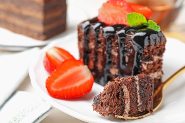 Çilek ve kaşıkla servis edilen bir parça çikolatalı pasta, yakın plan.