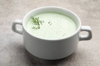 Gri masadaki dereotlu lezzetli salatalık çorbası, yakın plan.