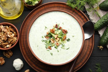 Dereotu ve cevizli lezzetli salatalık çorbası siyah ahşap masada servis edilir.