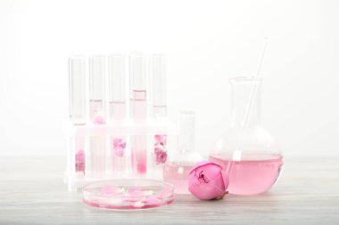 Lüks parfüm yapıyorum. Temel yağlar cam süslemede ve çiçekler beyaz ahşap masada, yakın plan.