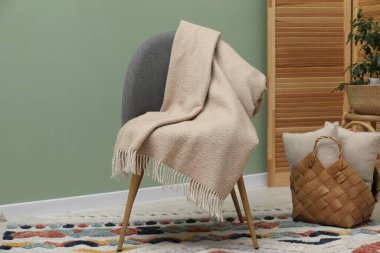 Yünlü battaniye ve yastıklı rahat bir koltuk.