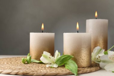 Beyaz masada yanan mumlar ve zambak çiçekleri.