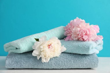 Yumuşak havlular ve şakayık çiçekler beyaz masada açık mavi arka planda, yakın plan