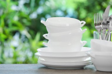 Ahşap masada, bulanık yeşil arka planda farklı temiz tabaklar.