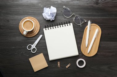 Düz kompozisyon ve siyah ahşap masa üzerinde boş bir defter.