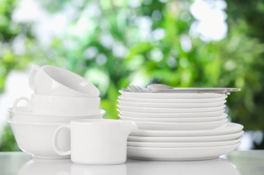 Bulanık yeşil arka planda beyaz masada farklı temiz tabaklar