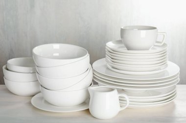 İçerideki açık ahşap masada farklı temiz bulaşık takımı.