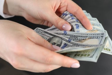 Gri arka planda dolar banknotları sayan kadın, yakın plan.