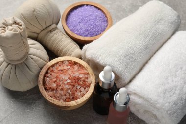 Bitkisel poşetler, kozmetik ürünler ve gri desenli masa üzerindeki havlularla kaplıca kompozisyonu