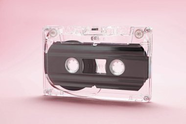 Pembe arka planda manyetik bantlı bir ses kaseti, yakın plan.