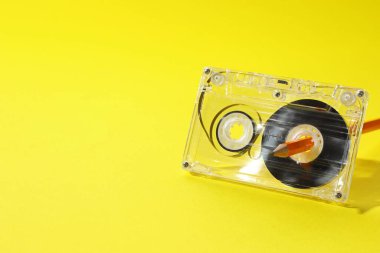 Sarı arka planda kurşun kalemle ses kaseti geri sarılıyor. Yakın plan. Metin için boşluk