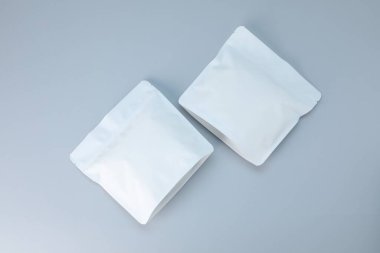 Açık gri arka planda iki fermuarlı stand-up kesesi, düz yatış. Tasarım için model