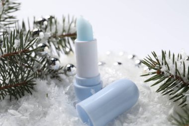 Nemlendirici dudak kremi, Noel dekorasyonu ve yapay kar üzerindeki köknar ağacı dalları, yakın plan. Kış bakımı