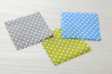 Beyaz ahşap masadaki farklı kumaşlardan örnekler, yakın plan.