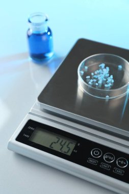 Petri kabı ve diğer cam parçalarıyla beyaz masa üzerindeki renk ışıklarıyla ölçeklendir, yakın plan