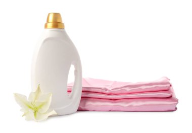 Bir şişe yumuşatıcı, üst üste yığılmış giysiler ve beyaz bir çiçek.