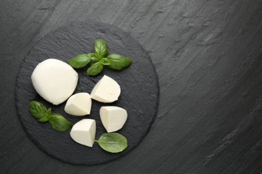 Lezzetli mozzarella peyniri ve fesleğen parçaları koyu dokulu masa, üst manzara. Metin için boşluk