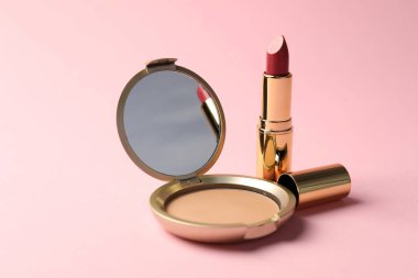 Aynalı açık yüz pudrası ve pembe arka planda ruj, yakın plan.