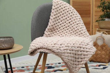 Yünlü battaniye ve dekorlu rahat bir koltuk.